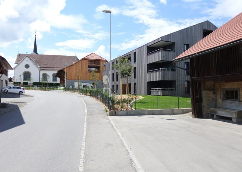 Construction moderne entourée de bâtiments plus anciens dans un village